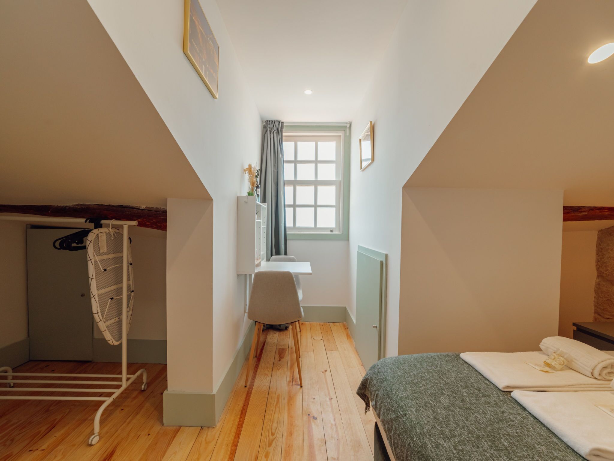 Ein schmales Zimmer mit einem Bett, einem Schreibtisch und einem Fenster.