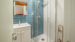 A modern bathroom with a glass shower enclosure, a white sink, and a mirror with a wooden accent. - Apartment  by Interhome (Porto)