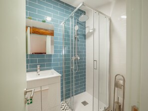 A modern bathroom with a glass shower enclosure, a white sink, and a mirror with a wooden accent. - Apartment  by Interhome (Porto)
