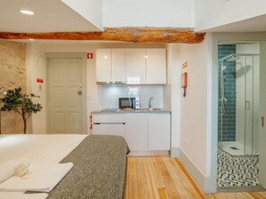 A compact hotel room with a bed, a kitchenette, a shower, and a small bathroom. - Apartment  by Interhome (Porto)