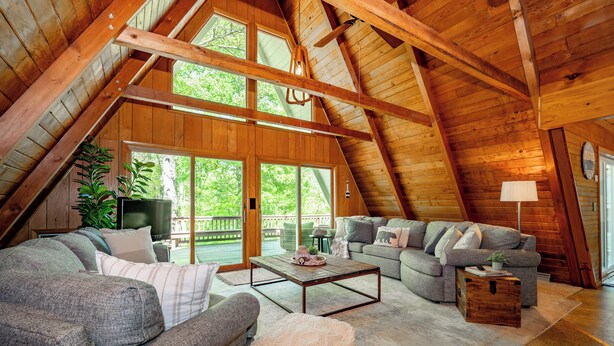 Tunnelmallinen, avoimen pohjaratkaisun mukainen olohuone, jossa on korkea katto, suuret ikkunat ja näkymä ulos.