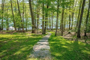 A stone pathway leading through a forested area with a lake in the background. - New! Beautiful Lake Views and Lake Fun! (McHenry)