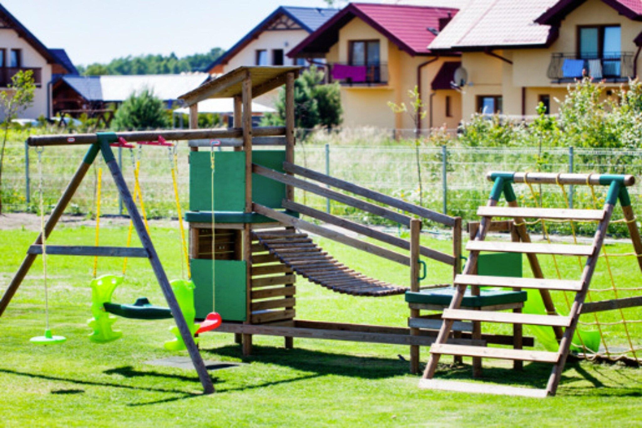 A playground with a slide, climbing net, and a ladder.