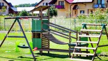 A playground with a slide, climbing net, and a ladder.