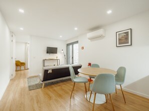 A modern living room with a dining area, wooden flooring, a flat-screen TV, and a fireplace. - Apartment  by Interhome (Porto)