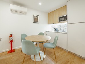 A modern kitchen with a microwave, a sink, and a dining area with a round table and four chairs. - Apartment  by Interhome (Porto)