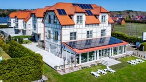 A modern building with multiple floors, large windows, and a red roof. - Beautiful and spacious apartment with a balcony (Debki)