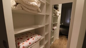 Ein Schlafzimmer mit einem Bett, einem Nachttisch und einem Kleiderschrank mit vielen Ablagen.
