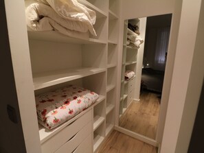 Ein Schlafzimmer mit einem Bett, einem Nachttisch und einem Kleiderschrank mit vielen Ablagen.