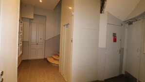 Ein Korridor mit Holzboden, einer weißen Tür und einer Treppe, die zu einer oberen Ebene führt.