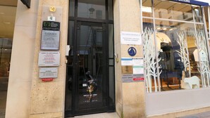 Ein Schaufenster mit einer schwarzen Tür und Glastüren, in denen Dummys ausgestellt sind.