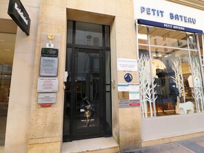 Ein Schaufenster mit einer schwarzen Tür und Glastüren, in denen Dummys ausgestellt sind.