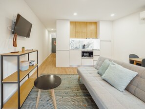 A modern living room with a sofa, a coffee table, and a television mounted on the wall. - Apartment  by Interhome (Porto)