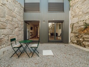 A building with a stone exterior, a gravel courtyard, and a green folding table with chairs. - Apartment  by Interhome (Porto)
