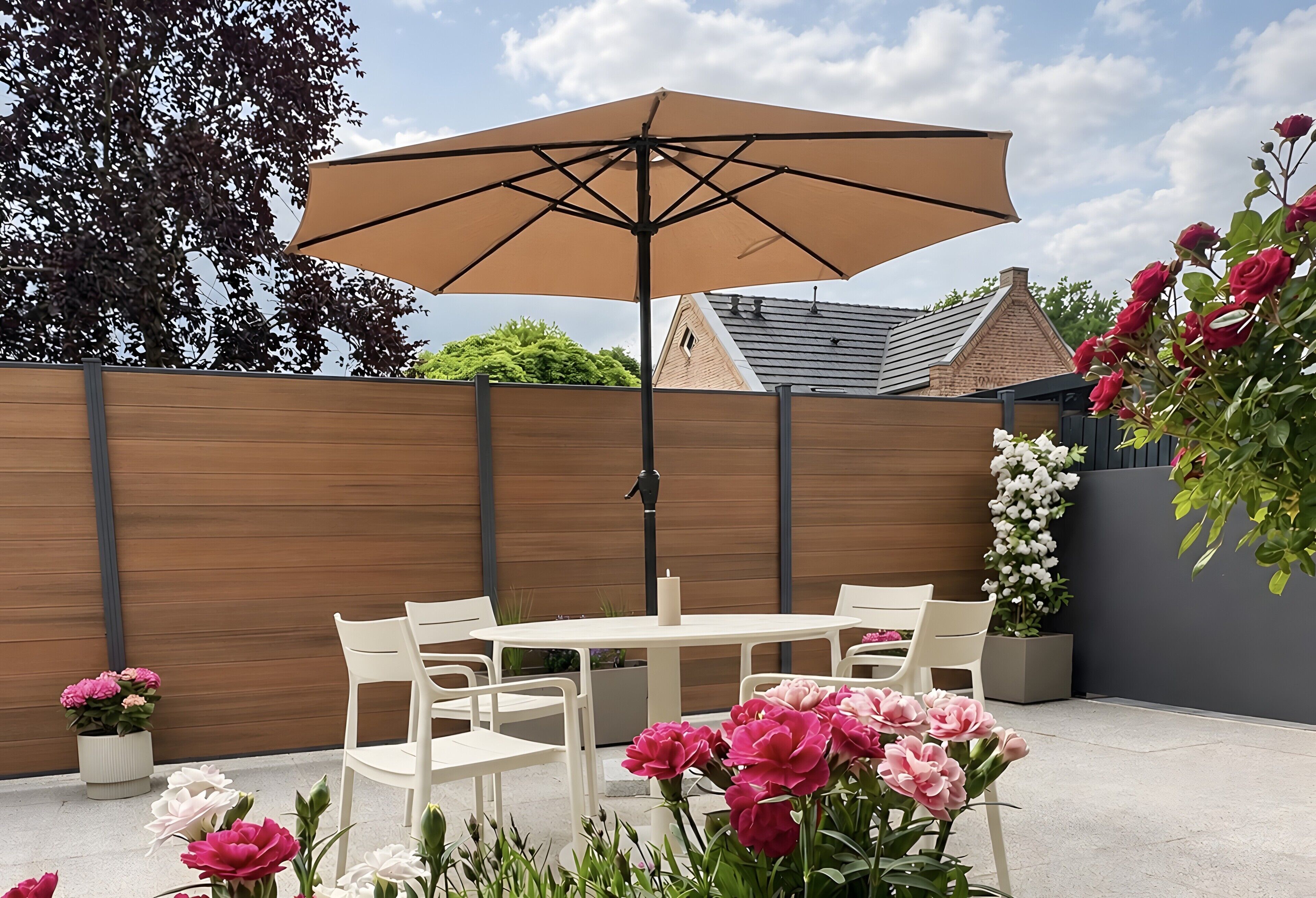 Une terrasse avec une table et des chaises, un parasol et des plantes en pot.
