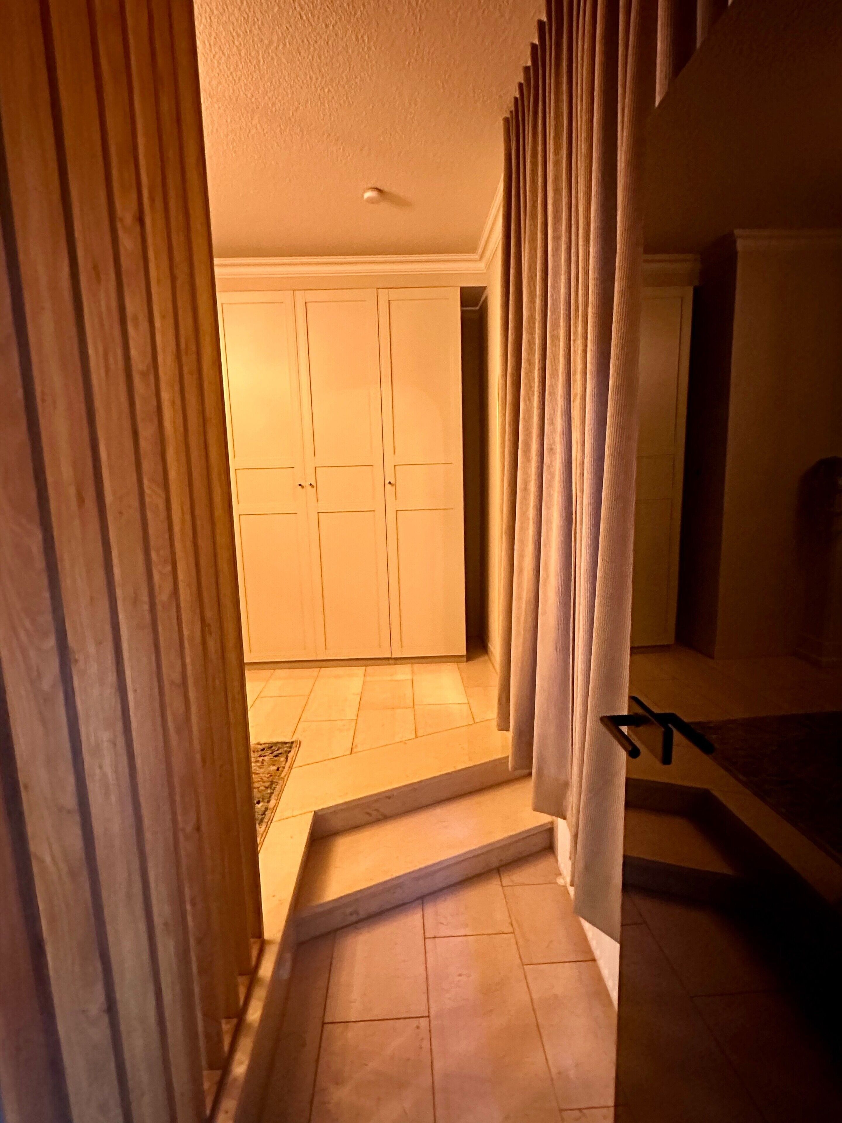 A hallway with a wooden door, a set of double doors, and a staircase leading to another room.