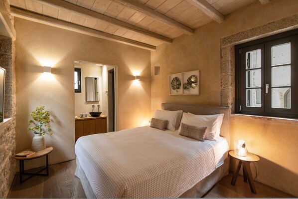 A bedroom with a bed, bedside table, lamp, and a wall-mounted mirror.