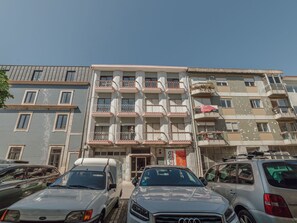 A multi-story building with balconies, a parking area with cars, and a clear sky. - Apartment  by Interhome (Porto)