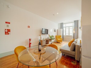 A modern living room with a glass dining table, yellow chairs, a sofa, a TV, and a fire extinguisher on the wall. - Apartment  by Interhome (Porto)