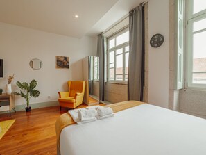 A hotel room with a large bed, a chair, a desk, a plant, and a window with curtains. - Apartment  by Interhome (Porto)