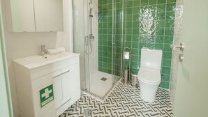 Une salle de bain avec un meuble-lavabo blanc, une cabine de douche en verre et des toilettes.