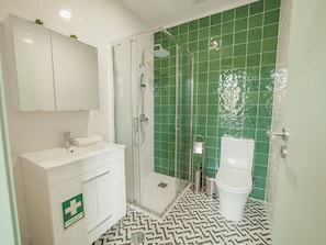 A bathroom with a white vanity, a glass shower enclosure, and a toilet. - Apartment  by Interhome (Porto)