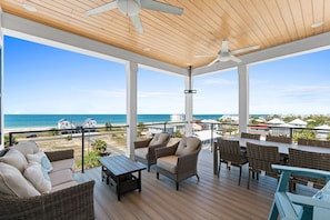 A covered outdoor area with wicker furniture, a table, and a view of the ocean. - Expansive Home in PSJ Beach, 3 Kitchens/Living and Dining areas! Private Pool (St. Joe Beach)