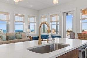 A modern kitchen with a large island, a gold faucet, and a view of the sea. - Expansive Home in PSJ Beach, 3 Kitchens/Living and Dining areas! Private Pool (St. Joe Beach)