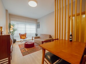 A modern living room with a wooden dining table, a sofa, a red ottoman, and a chair. - GOOD MORNING APARTMENT with GARAGE by VACATIONY by Interhome (Porto)