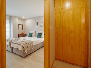 A bedroom with a bed, bedside tables, a wardrobe, and a window. - GOOD MORNING APARTMENT with GARAGE by VACATIONY by Interhome (Porto)