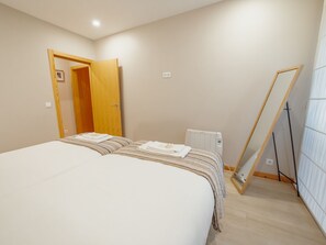 A bedroom with a large bed, a wooden door, a radiator, and a mirror leaning against the wall. - GOOD MORNING APARTMENT with GARAGE by VACATIONY by Interhome (Porto)