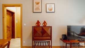 Un saló amb un armari de fusta, dues obres d'art emmarcades, una televisió i una taula de menjador amb caires.