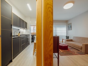 A modern kitchen with dark cabinets and a wooden dining table. - GOOD MORNING APARTMENT with GARAGE by VACATIONY by Interhome (Porto)