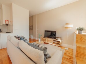 Ein modernes Wohnzimmer mit einer Couch, einem Fernseher und Holzböden.