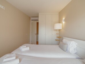 Une chambre d’hôtel avec un lit, une table de chevet, une lampe et une armoire.
