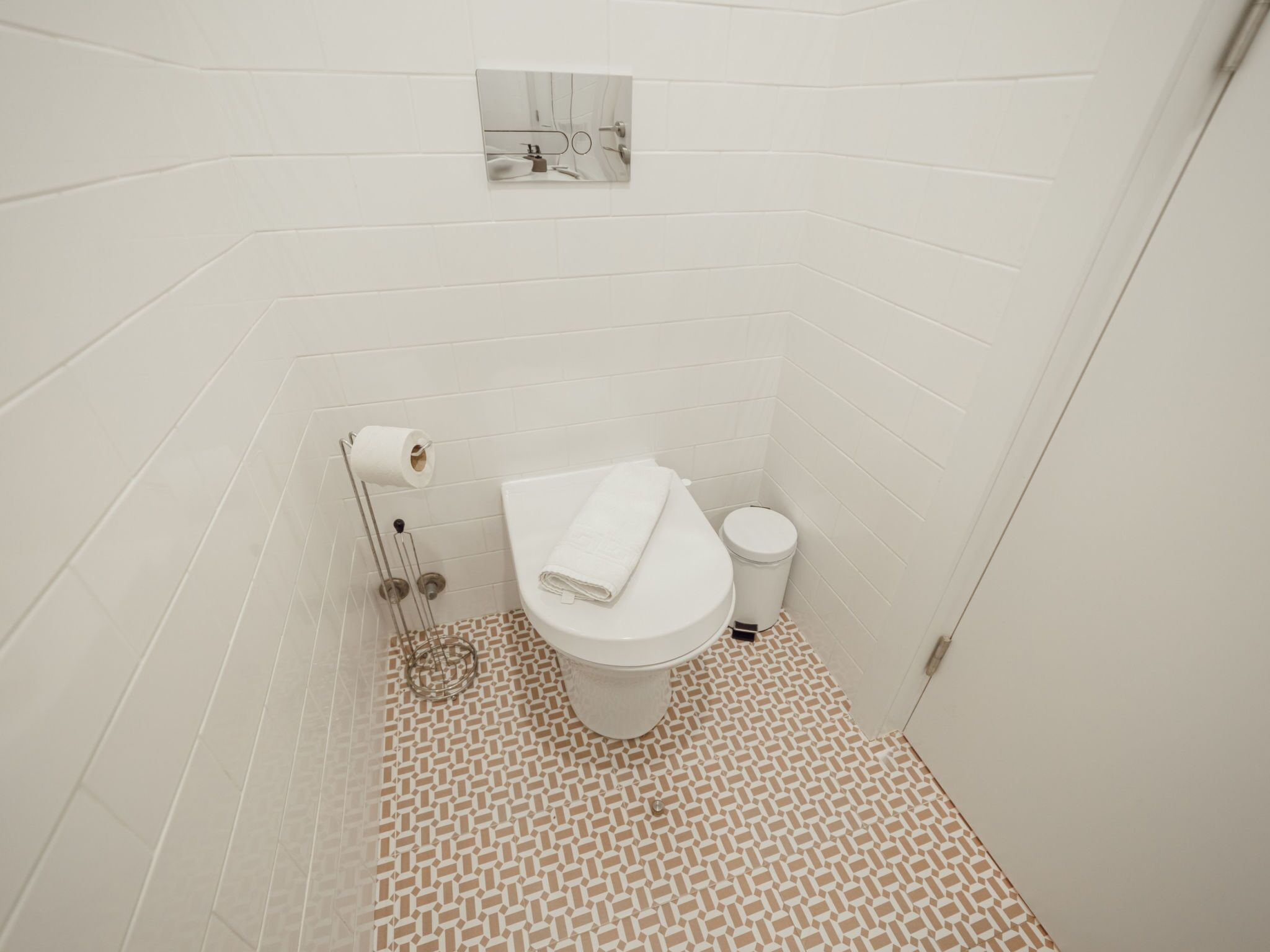 Ein kleines, weißes Badezimmer mit Toilette, Mülleimer und Toilettenpapierhalter.