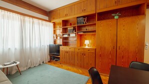 Ein Wohnzimmer mit Holzausbau, einem Fernseher, einem kleinen Tisch und einem Sofa.