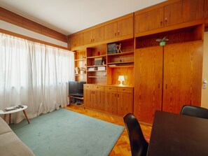 Ein Wohnzimmer mit Holzausbau, einem Fernseher, einem kleinen Tisch und einem Sofa.