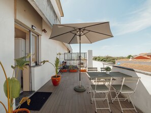 An outdoor balcony with a table and chairs, a potted plant, and a large umbrella. - Apartment  by Interhome (Porto)