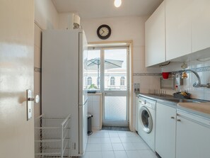 Una cocina compacta con lavadora, refrigerador y un reloj en la pared.
