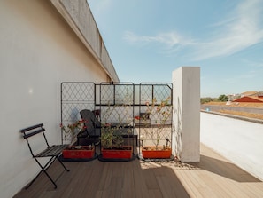 Une terrasse sur le toit, avec un banc, une chaise et des plantes en pot.