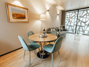 Un intérieur moderne avec une table de salle à manger ronde, deux chaises, un canapé et un lampadaire.