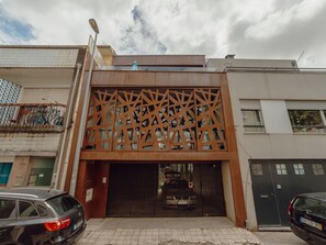 Un immeuble à la façade moderne, doté d’une entrée sécurisée et avec des voitures garées devant.