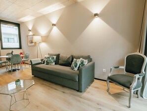 Un salon moderne avec un canapé gris, une table basse en verre et un fauteuil décoratif.