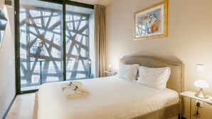 Hotellihuone, jossa on suuri sänky, yöpöytä, lamppu ja taulu seinällä.