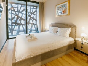 A hotel room with a large bed, a nightstand, a lamp, and a painting on the wall. - Apartment  by Interhome (Porto)