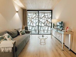 A modern living room with a sofa, a glass coffee table, and a TV on a cabinet. - Apartment  by Interhome (Porto)