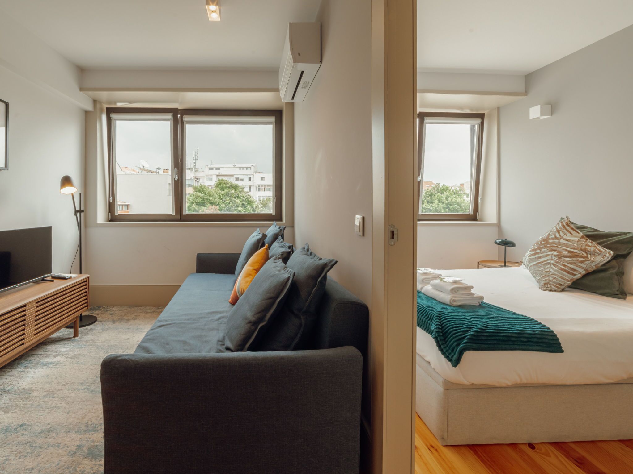 Ein modernes Schlafzimmer mit einer Couch, einem Bett und einem Fernseher.