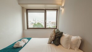 A hotel room with a bed, a window, and a view of buildings. - Apartment  by Interhome (Porto)
