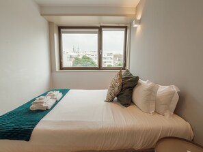 Quarto de hotel com cama, janela e vista para edifícios.